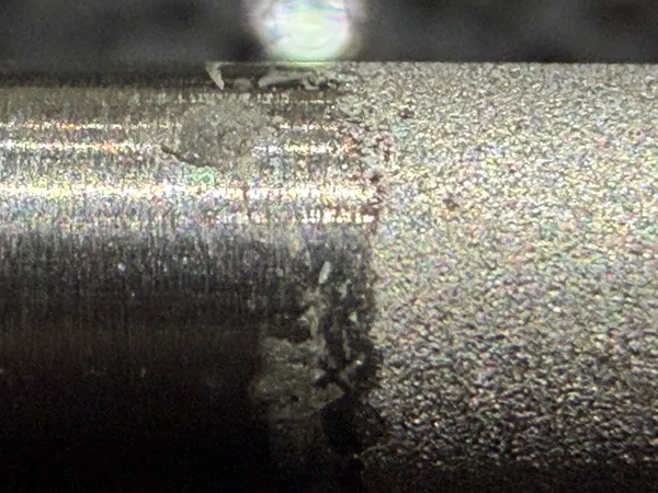 Macro photo of a platinised titanium rod with a rough grey coating, with a smoother patch near one end