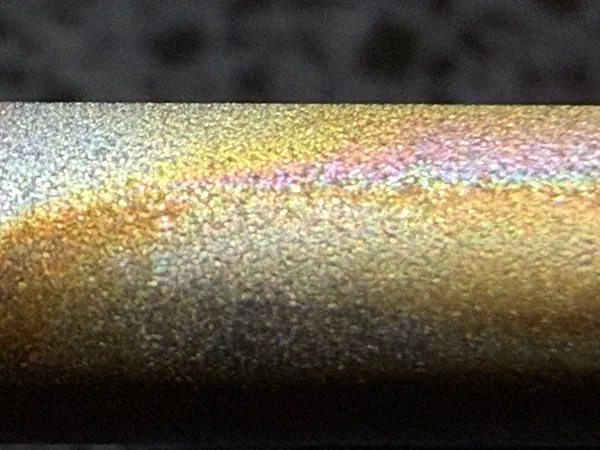 Macro photo of a discoloured electrode rod with a smear where it has been wiped, showing brighter metal underneath
